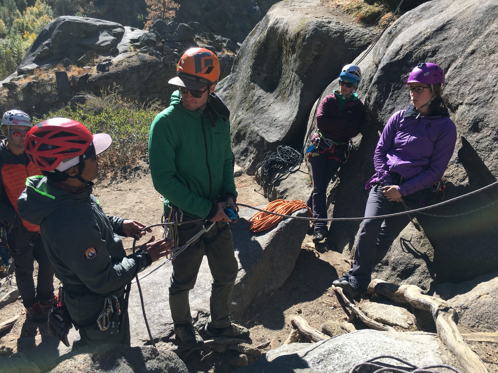 Climbers linked up on a rope talking next to some boulders