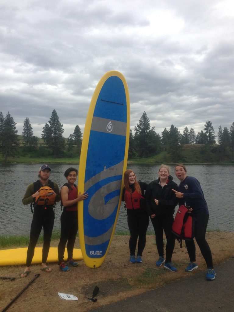 Surfboarders posing around a surf board