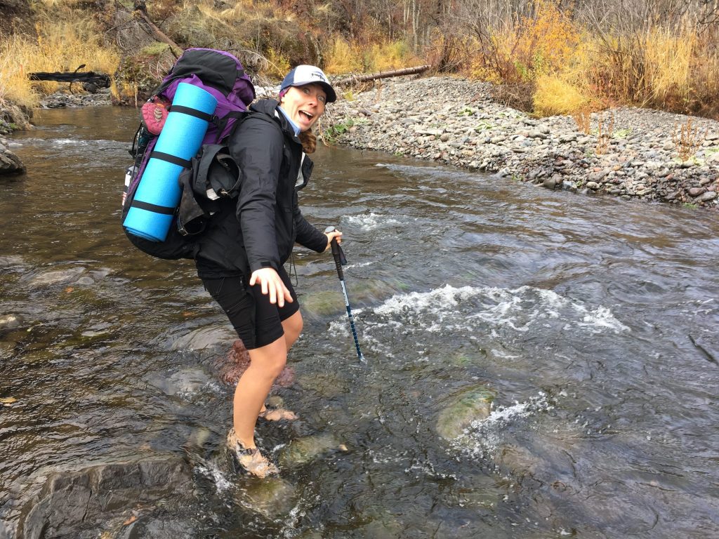 Backpacker walking through a river