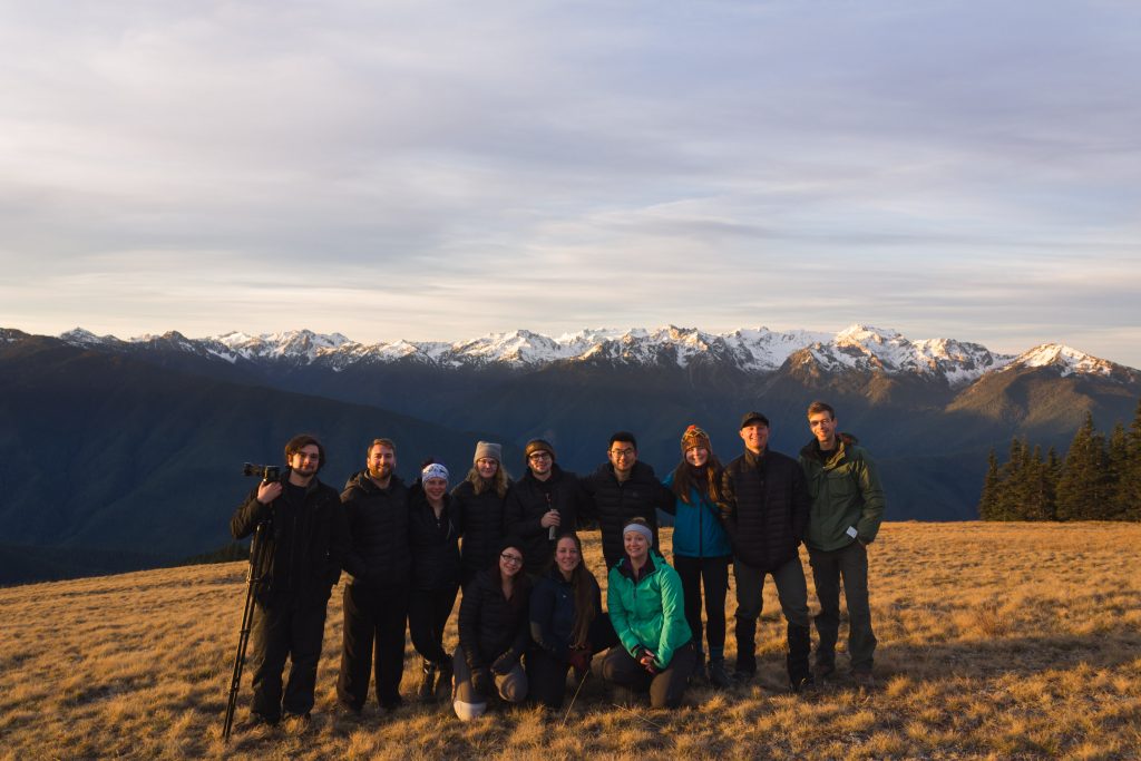 Group of people standing in freont of a mountain posing for a photo