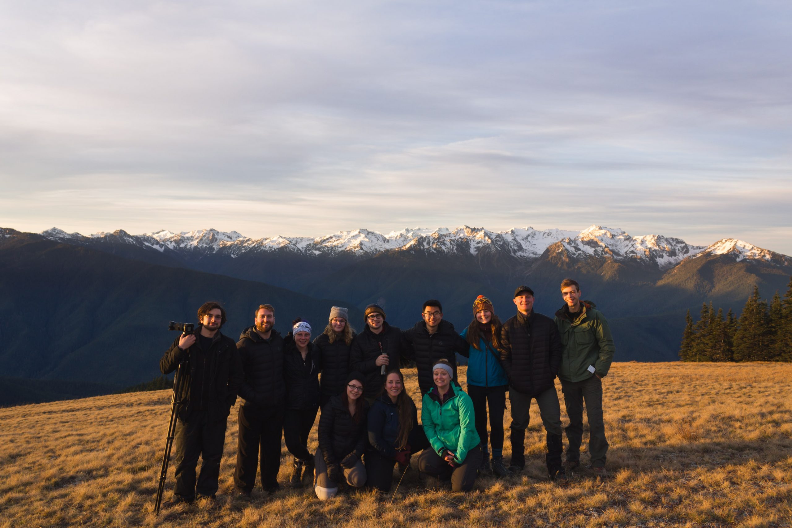 Group of people standing in freont of a mountain posing for a photo