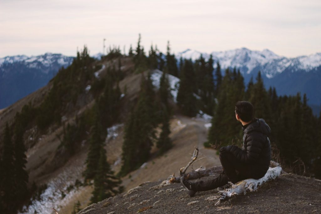 Man sitting on top of a mountain looking at the horizon