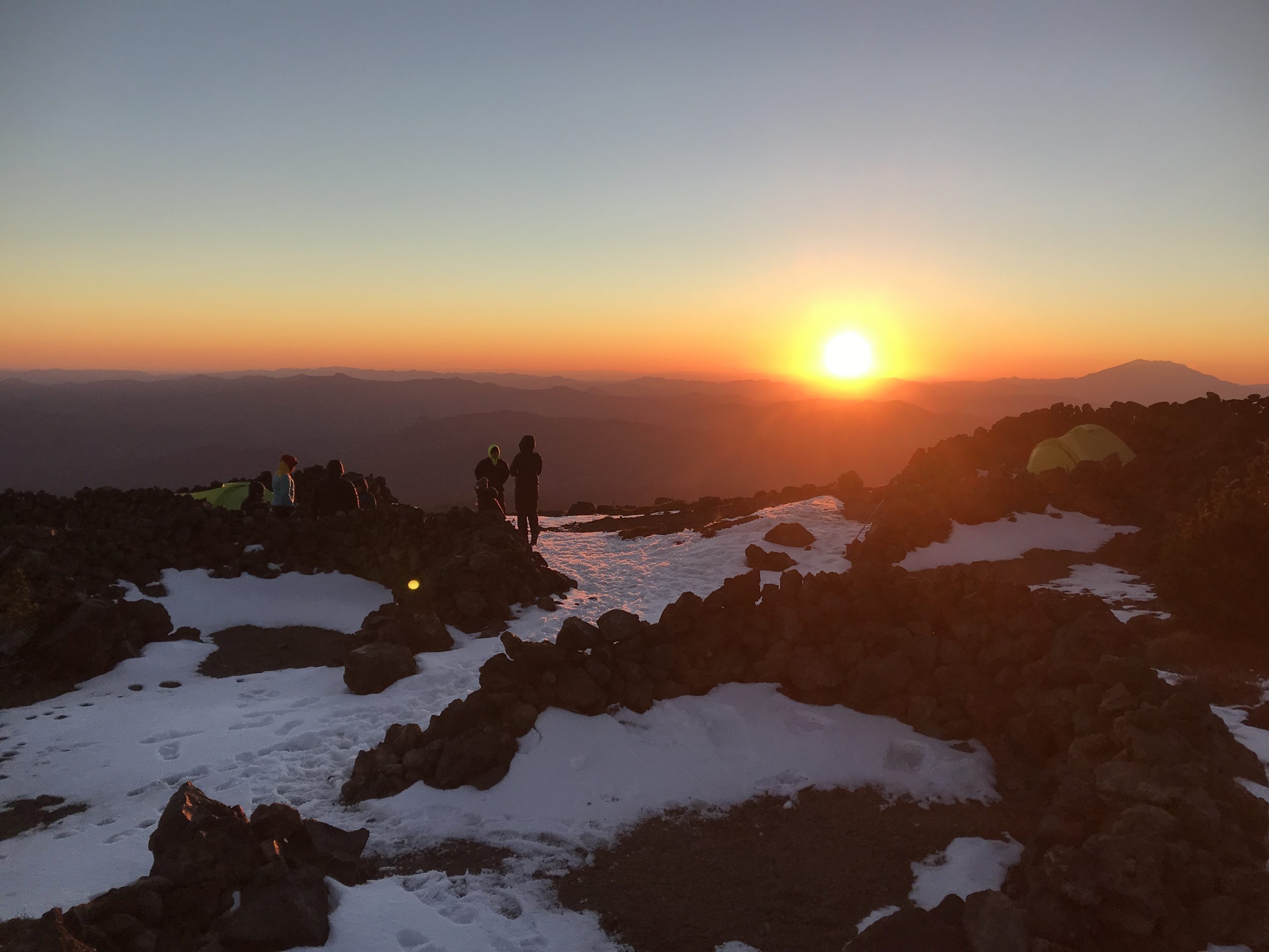 Hikers on top of a mountain during sunset