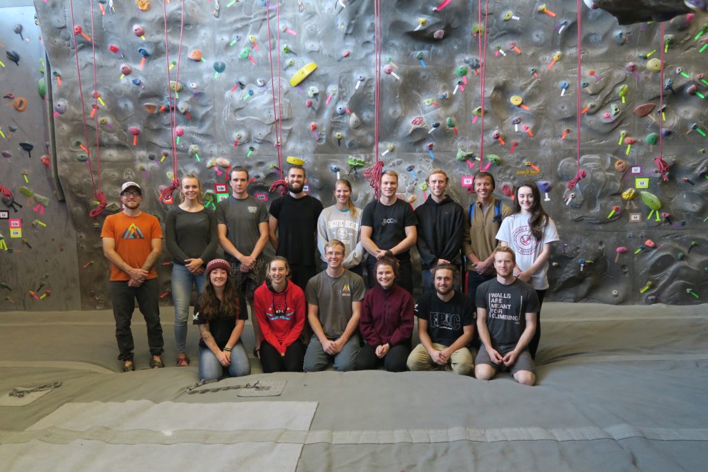 group of people sitting in front of a rockwall