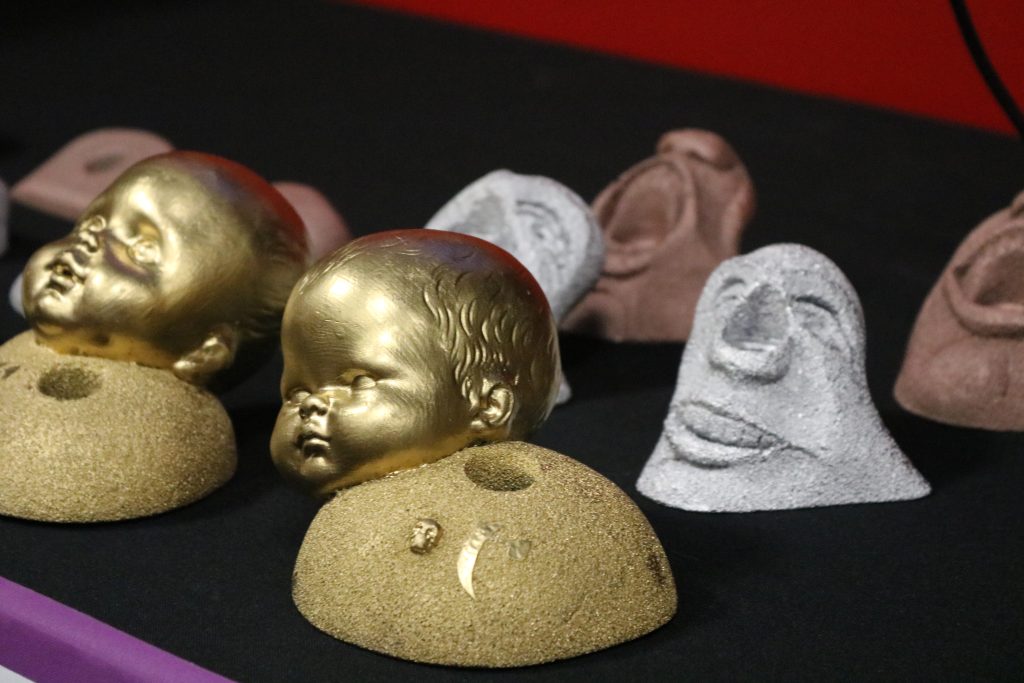 Golden baby head on a rock climbing rock and a statue head