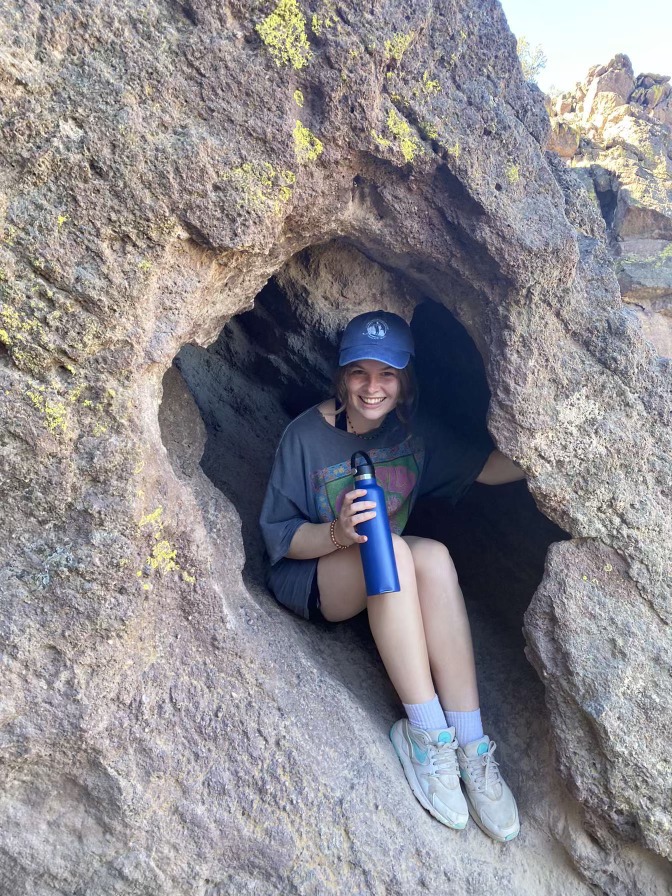 Maddie G. - Customer Service Representative and Equipment Technician, sitting inside a rocky crevice