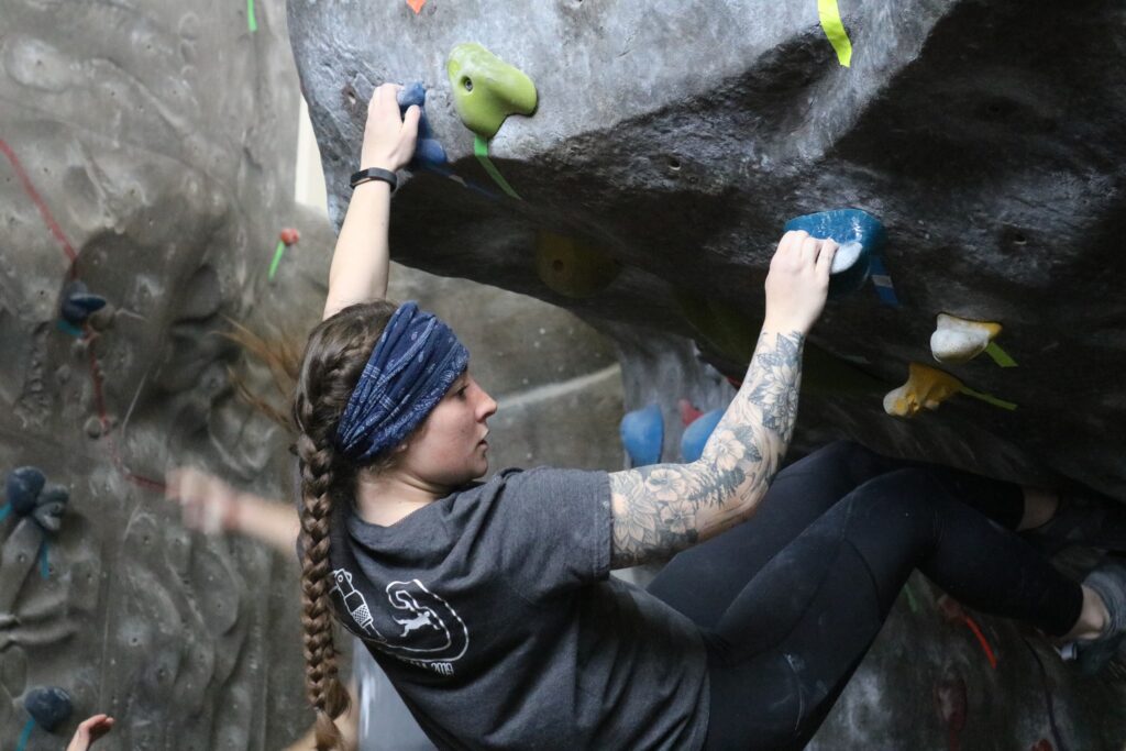 Woman scaling climbing rock wall