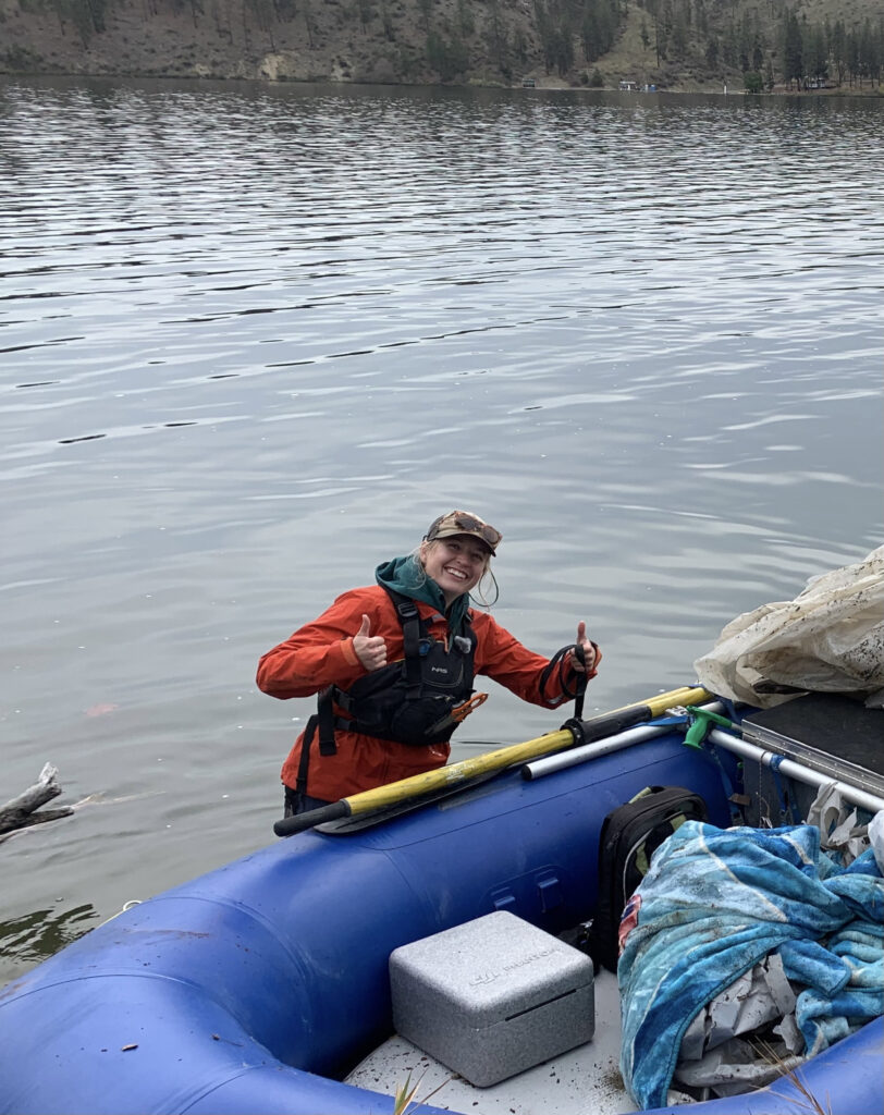 Liv K. - Field Staff knee deep in a lake next to a raft