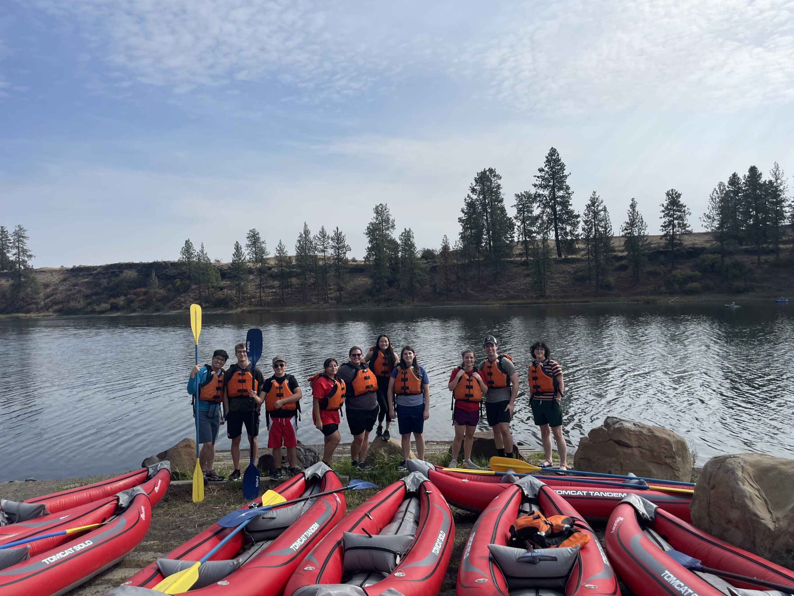 Group of kayakers posing with their paddels in front of their kayaks