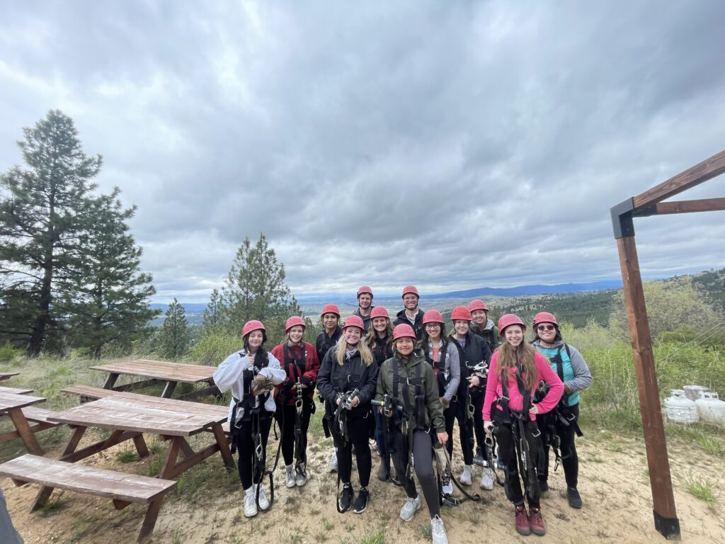 Group of people standing next to a picnic table in the forest