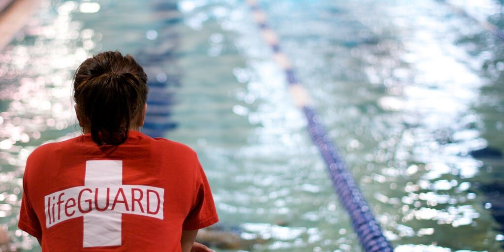 a lifeguard sits next to the pool