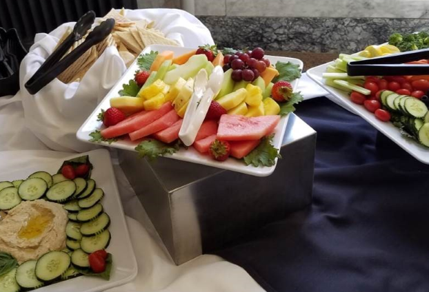 photo of fruit platter on a table. Along with the fruit platter, there is a veggie tray and a basket of tortillas