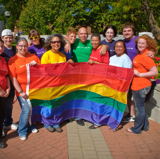 People gathered around holding the pride flag