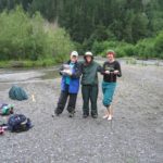 Three people posing for a picture near a river bed