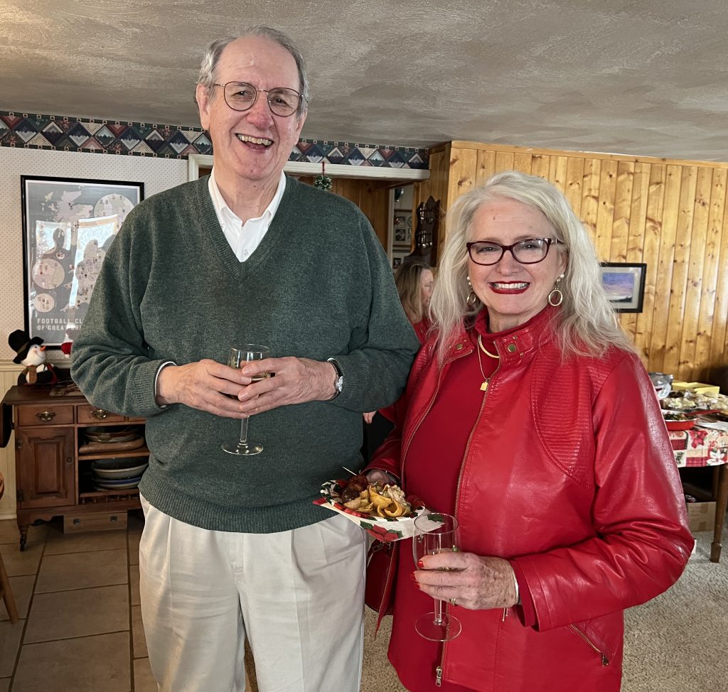 Photo of two people, standing, holding glasses and food