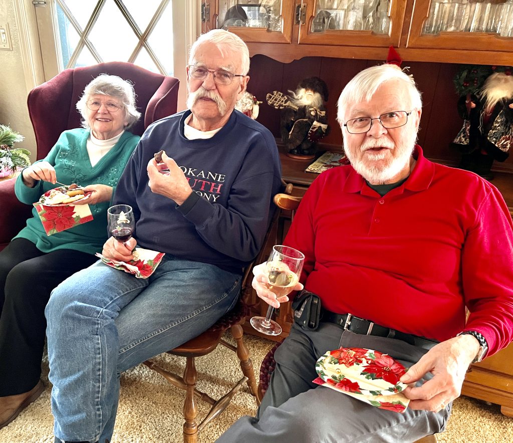 Three people sitting, eating food