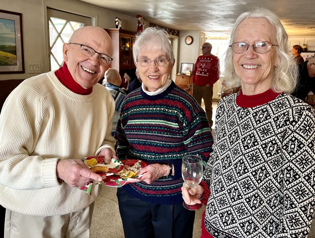 Three people, standing, holding food and smiling at the camera