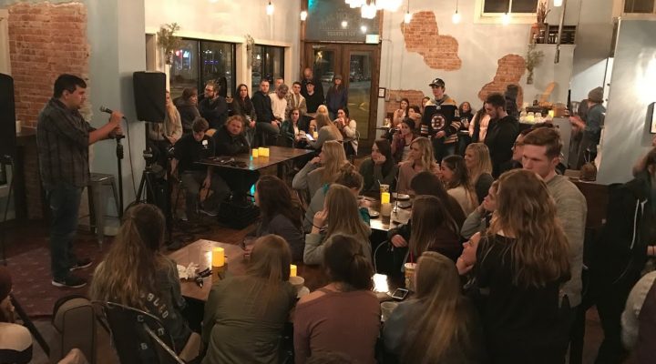 Group of people in the mason jar restaurant watching as someone preforms on a small stage