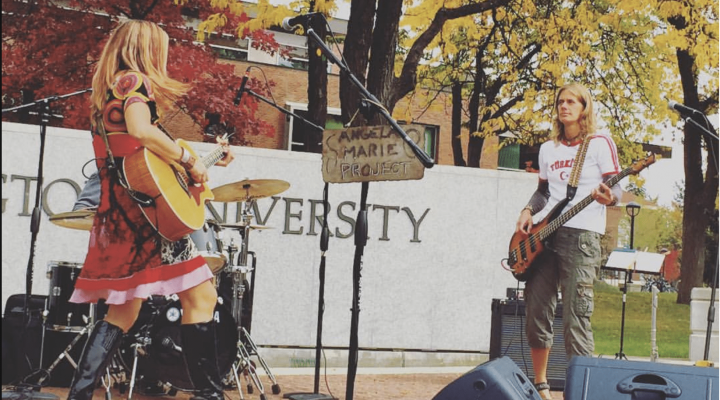 Two students playing a guitar and bass in the campus mall during a band preformance