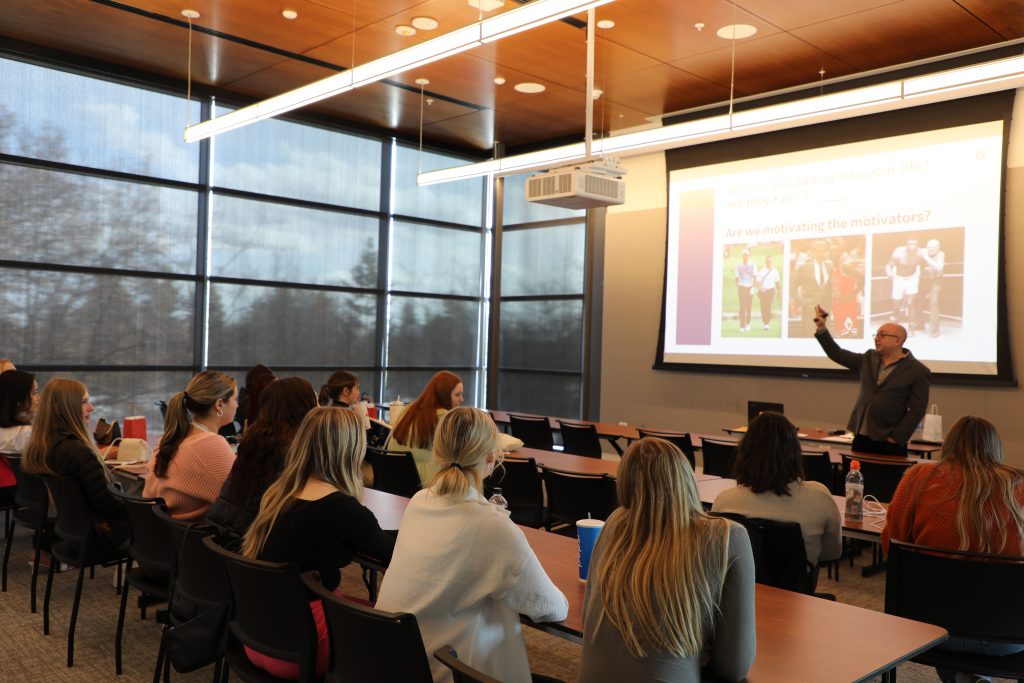 Students attending a talk in one of the PUB rooms. There is a man giving a talk in front of the people with a projector