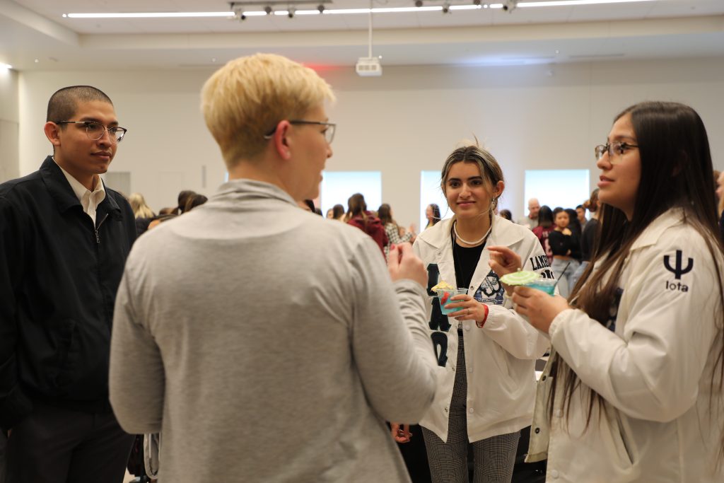 Group of people standing in the Nysether Community Room having a discussion.