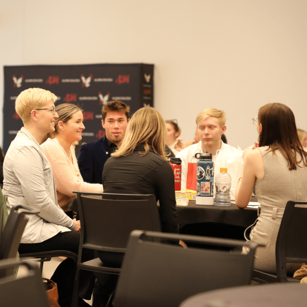 People conversing at tables in the Nysether Community Room in the PUB.