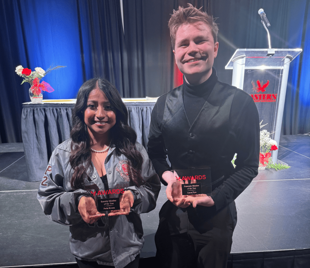 Photo of two people holding awards