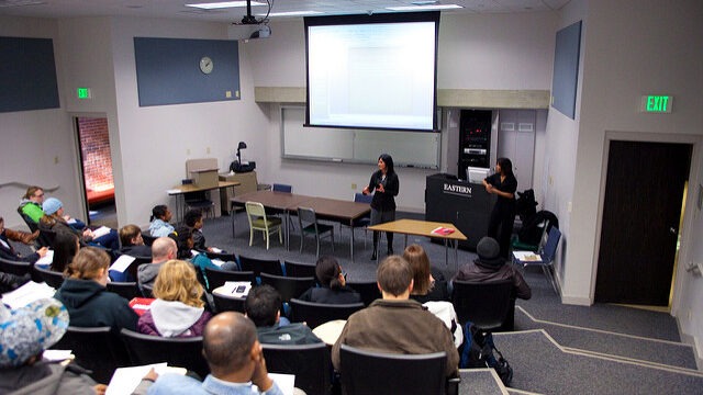 A person in a lecture room presenting to a group of people